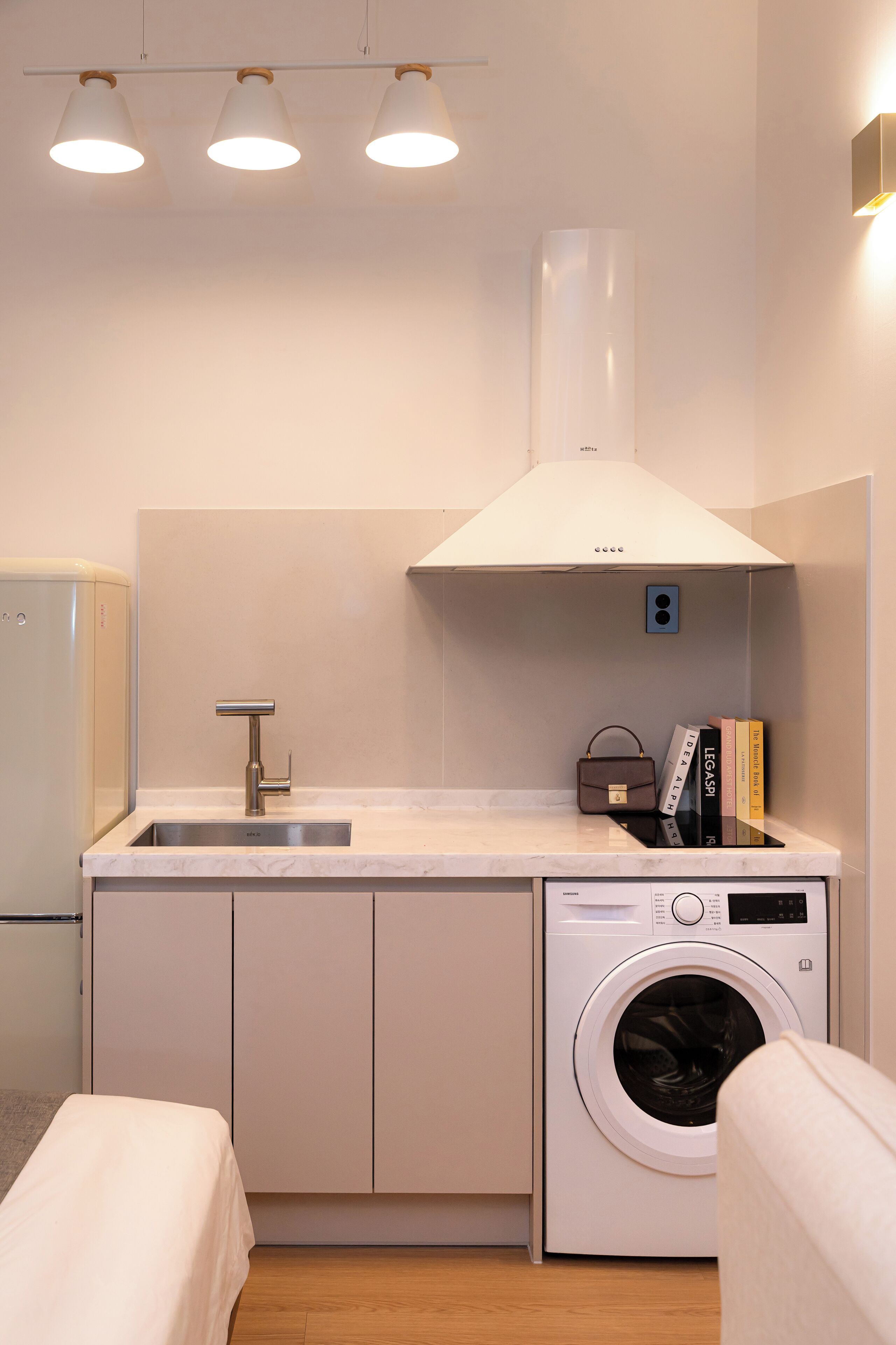 A compact kitchenette with a sink, a built-in washing machine, and a small countertop.