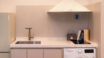 A compact kitchenette with a sink, a built-in washing machine, and a small countertop.