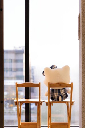 Two wooden chairs facing a window with a view of buildings. - STAY On-A (Seoul)