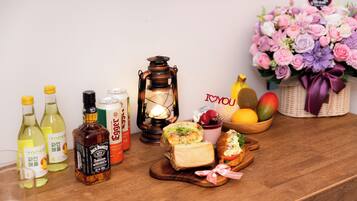 A wooden table with various items including bottles, a lantern, sandwiches, fruits, and a floral arrangement.