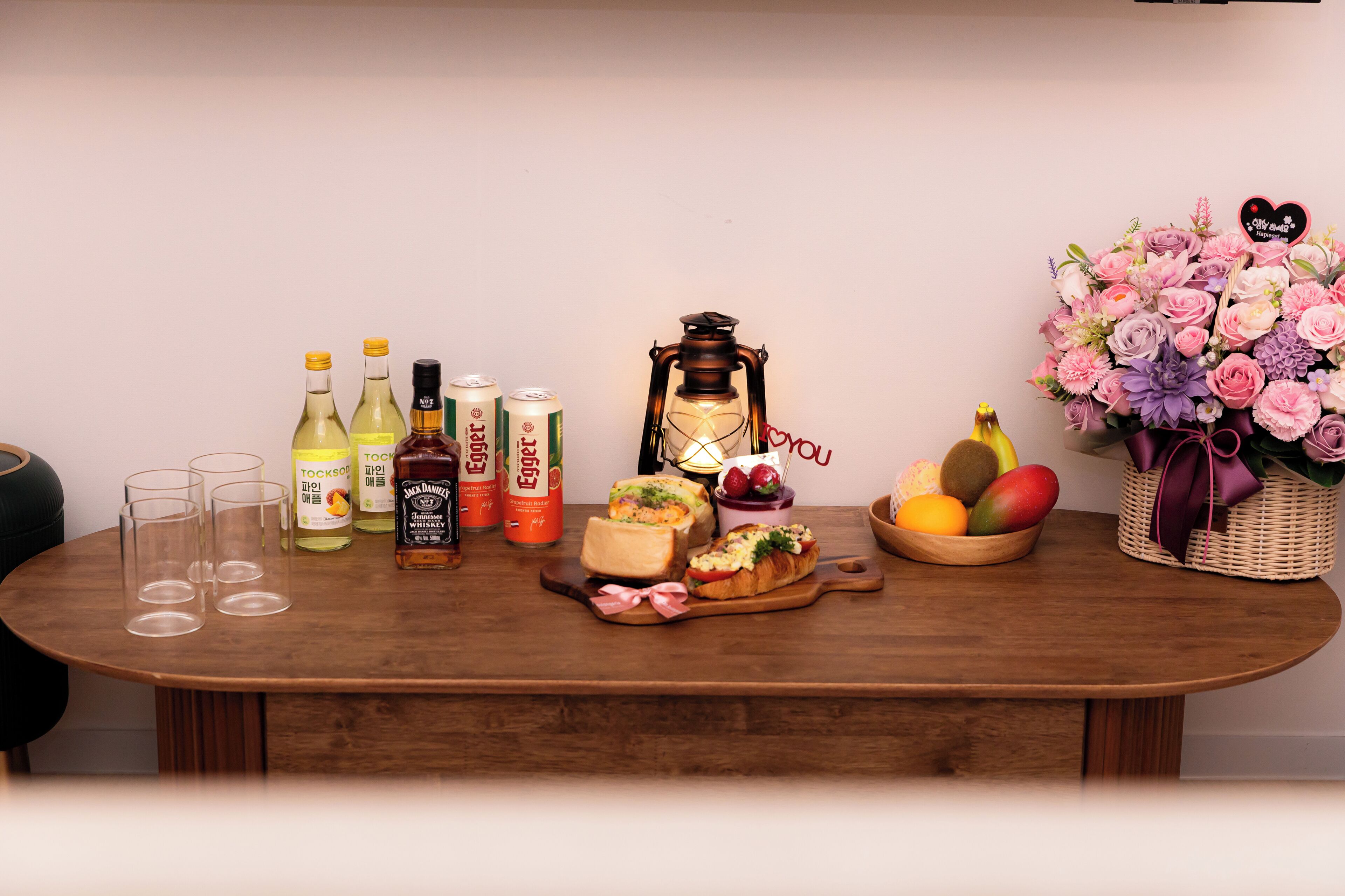 A wooden table with various food items, drinks, and a lantern.