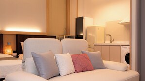 Una sala de estar moderna con sofá, lavadora y zona de cocina.