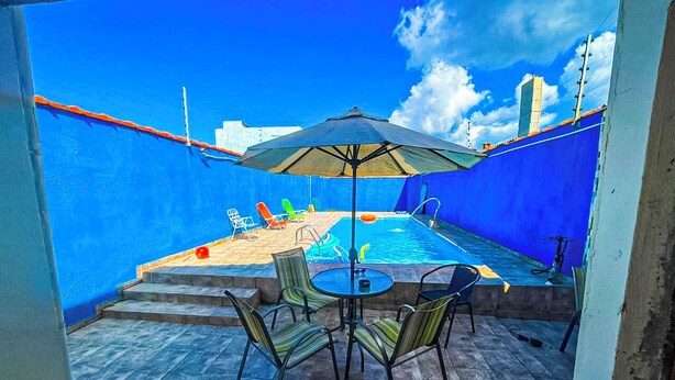 A patio with a pool, outdoor seating, and a blue wall.
