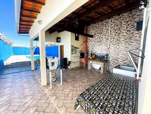 Una zona exterior coberta amb un paviment de rajoles, una piscina blava i una paret de maó.