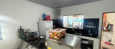 A compact living space with a kitchenette, a sofa, a TV, and a window with blinds.