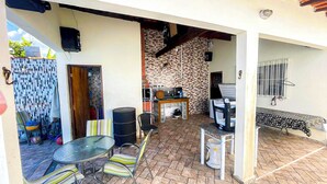 An outdoor patio with a table and chairs, a grill, and a tiled wall.