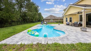 Ein Garten mit Swimmingpool, Terrassenmöbeln und einem Haus.