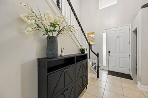 Una escalera con un elegante consola negra y un jarrón de flores blancas.