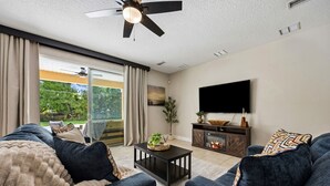 Ein Wohnzimmer mit Sofa, Couchtisch, Fernseher und Kamin.