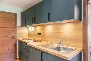 Une cuisine moderne avec des meubles en bois, un évier en acier inoxydable et un éclairage intégré sous le plan de travail.