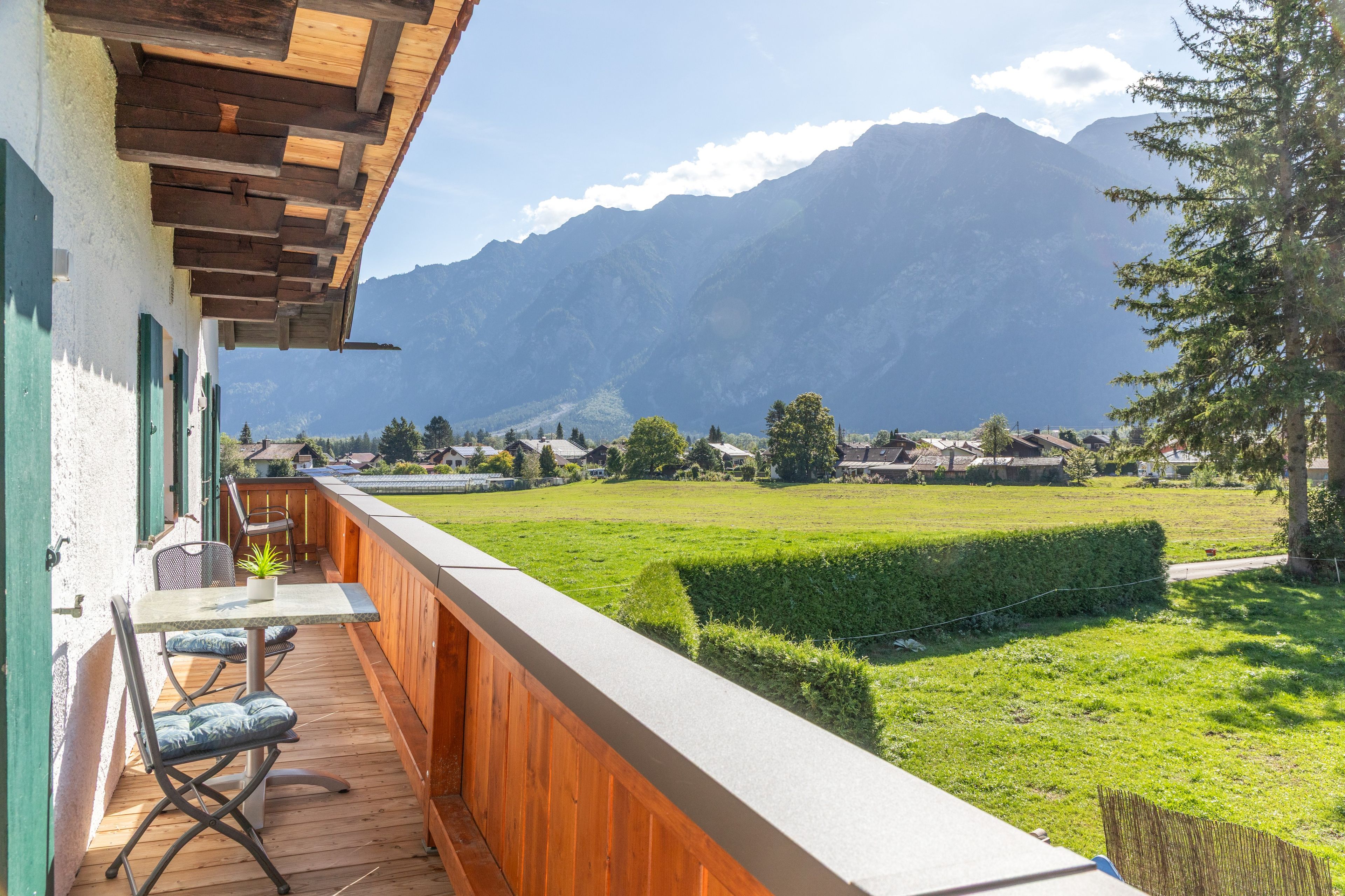 Ein Balkon mit Holzboden, einem Tisch und einem Stuhl.