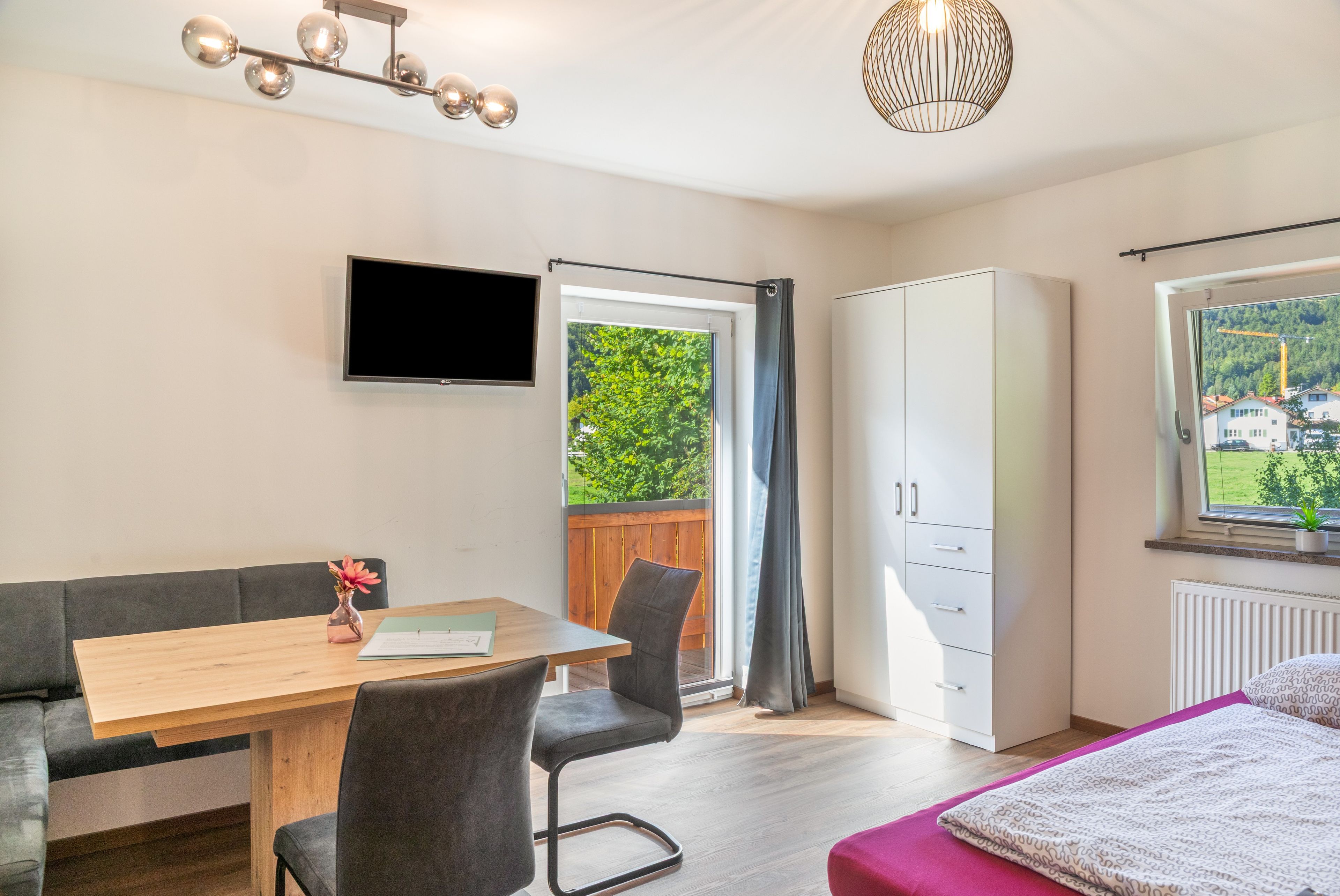 Ein modernes Schlafzimmer mit Bett, Schreibtisch, Stuhl, Kleiderschrank und Fernseher.