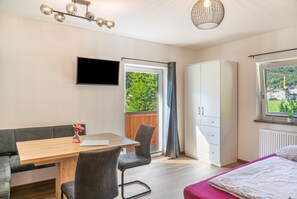 Une chambre à coucher moderne, comprenant un lit, un bureau, une chaise, une armoire et un téléviseur.