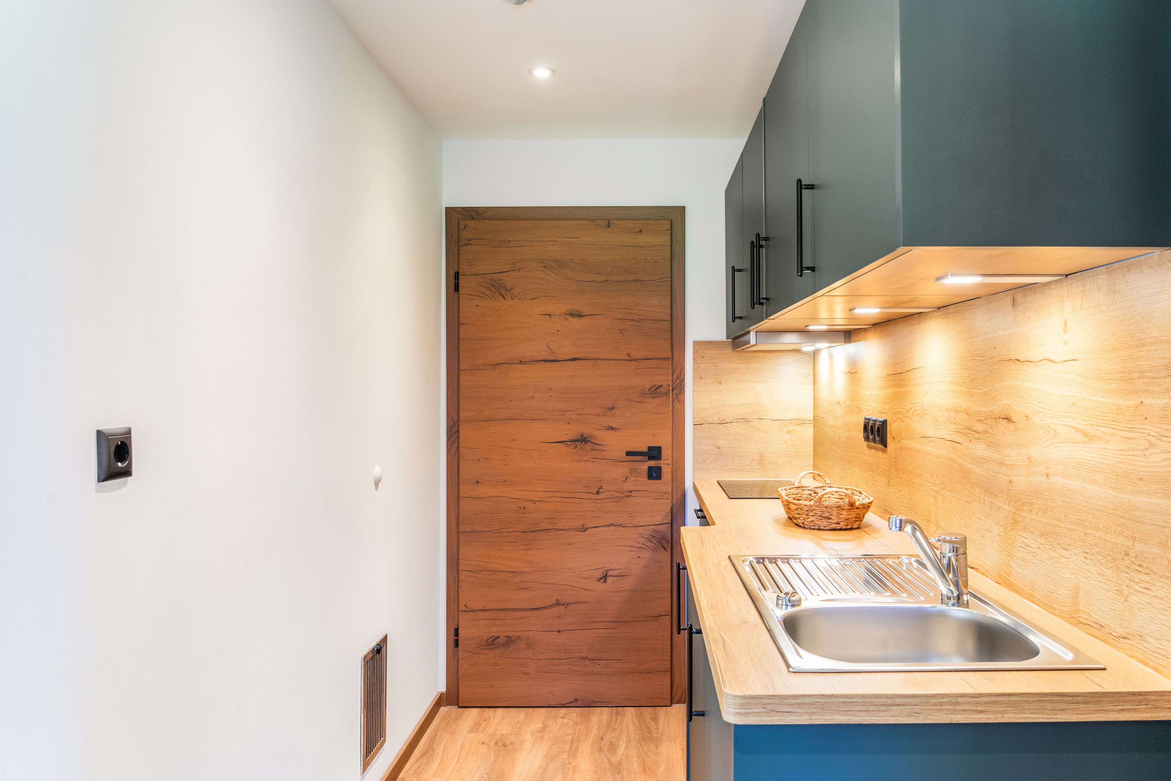 Eine moderne Küche mit Holztür, Edelstahlspüle und Holzschränken.