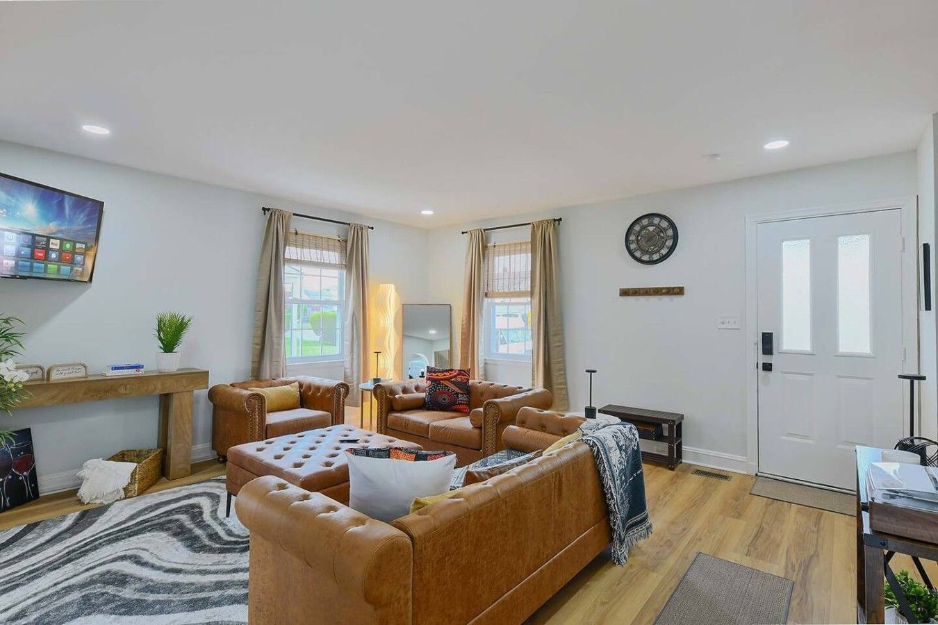 A modern living room with a sofa set, a coffee table, and a television mounted on the wall.
