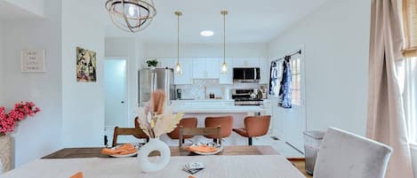 Una cocina moderna con armarios blancos, una isla central e iluminación colgante.