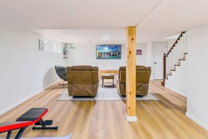 Un salon avec deux canapés, une petite table, un banc rouge et un escalier.