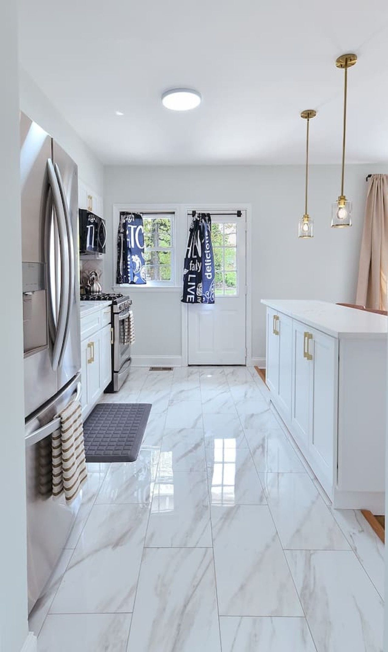 A modern kitchen with white cabinetry, a stainless steel refrigerator, and a gas stove.
