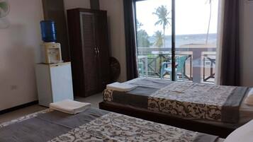 A hotel room with a bed, a wardrobe, a small fridge, a water dispenser, and a balcony with a view.