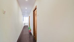 Un long couloir étroit, doté d’un plancher sombre, de murs blancs et d’une porte en bois au bout.