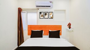 Une chambre d’hôtel avec un lit, une fenêtre avec des rideaux, un appareil de climatisation et des œuvres d’art murales.