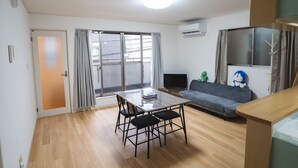 A living room with a dining table, chairs, a sofa, and a TV. - ODA VILLA@Umeda (Osaka City)