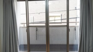 Janela com vista para um edifício com fachada de tijolos e varanda.