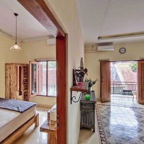 Amplia habitación con una gran mesa de madera, una lámpara colgante y vistas a un patio empedrado.