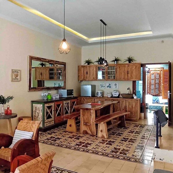 Una cocina con armarios de madera, una mesa de comedor y un banco. Hay un espejo grande sobre la encimera y una lámpara colgante.