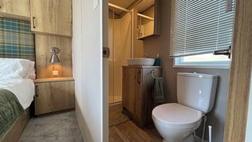 A compact bathroom with a toilet, sink, and shower.