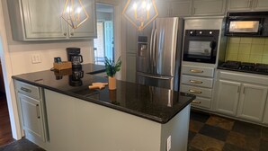 A kitchen with a central island, stainless steel appliances, and pendant lighting.