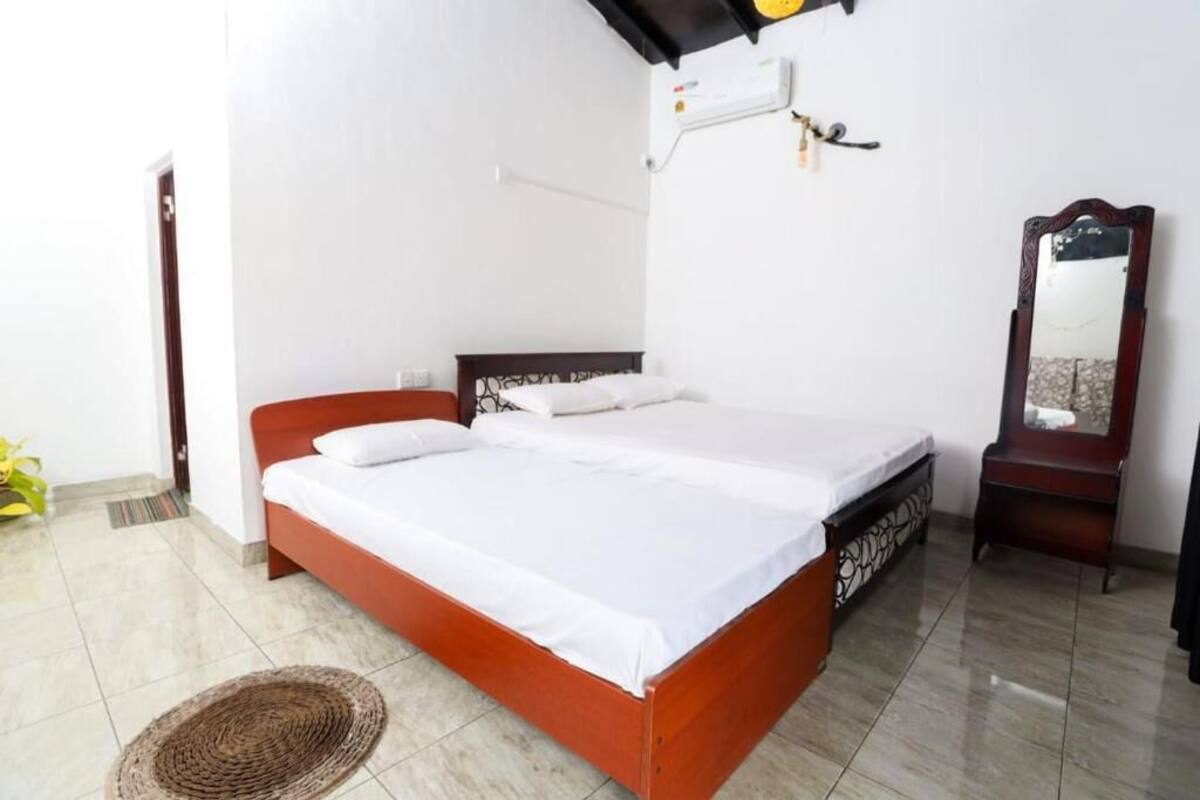 A bedroom with a bed, a bedside table, a mirror, and a wall-mounted air conditioning unit.