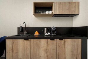 Eine moderne Küche mit einer Holzauskładung, einem eingebauten Ofen, einer Kaffeemaschine und einem Regal über der Spüle.