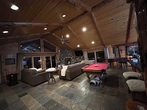 Ein gemütlicher Innenraum mit Billardtisch, Sofas und Kamin aus Stein.