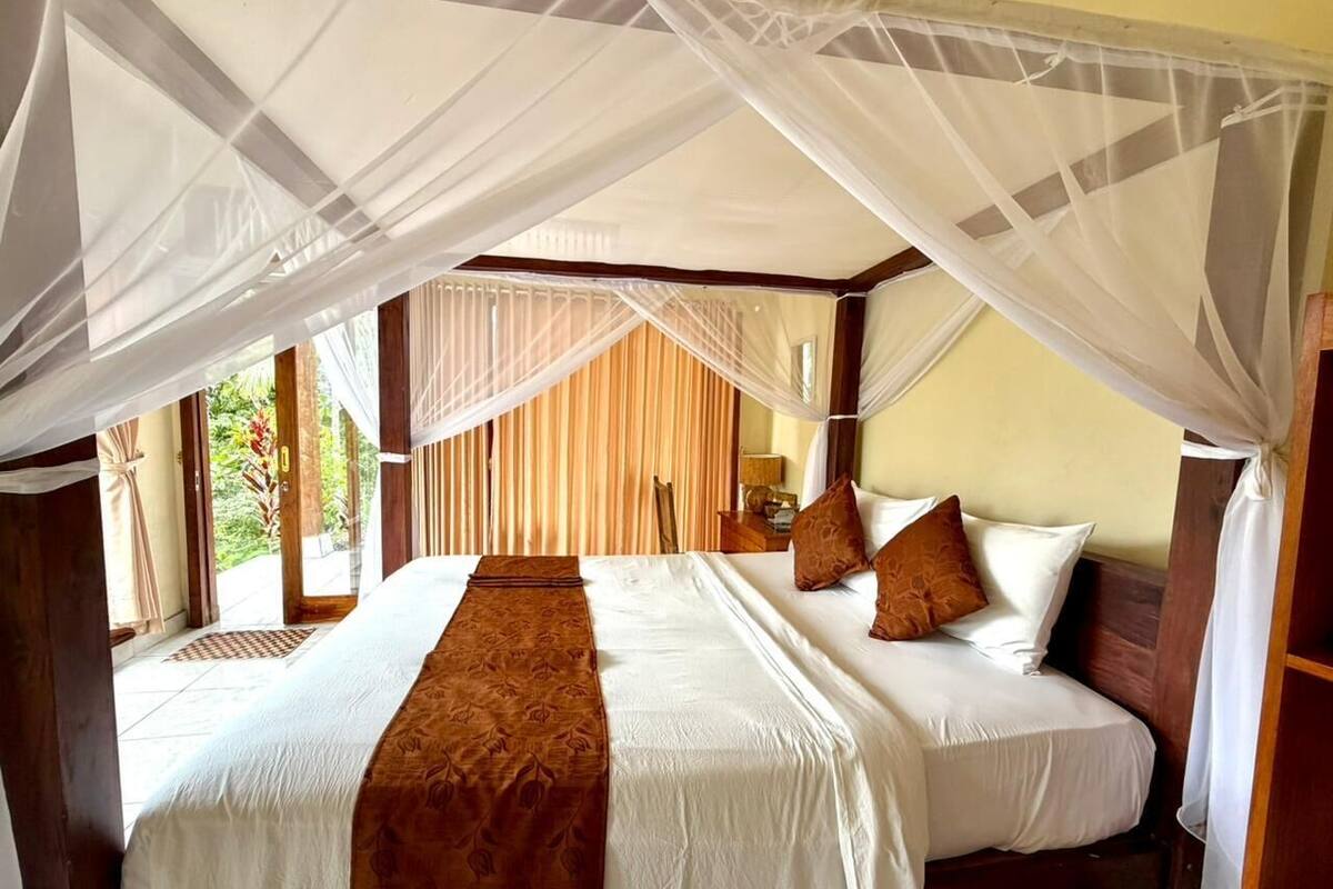 Una cama doble con dosel, cabecera de madera y un corredor decorativo marrón.