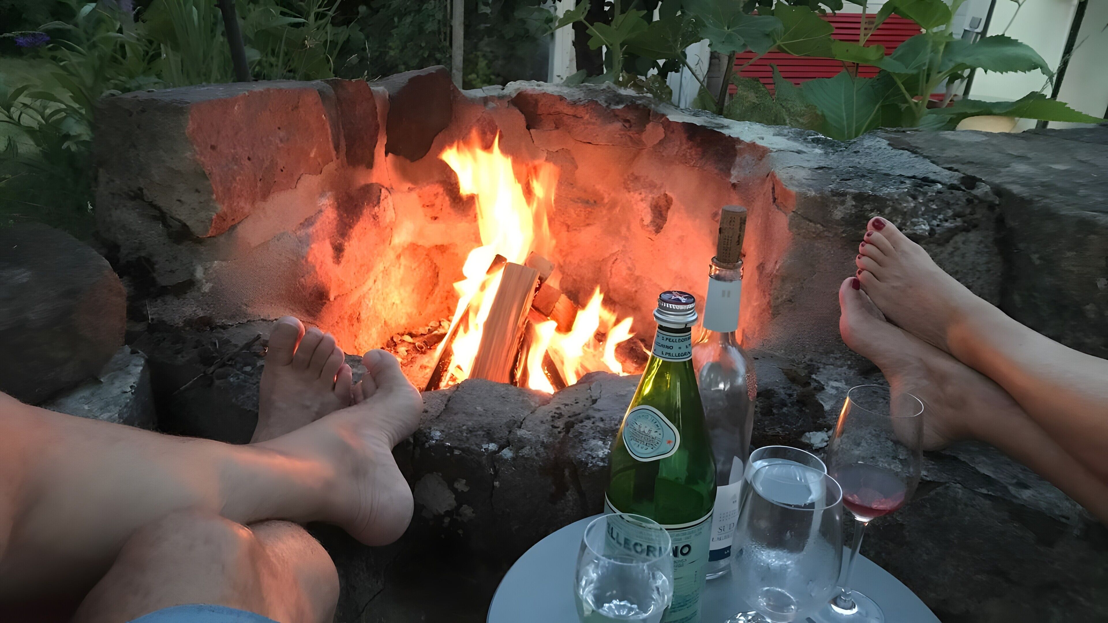 Een vuurkorf met een fles en glazen op een tafel.