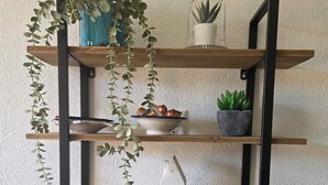 A black marble table with a wooden shelf unit holding plants, a bowl, and a small white house-shaped object. - Cocon Neuf & Vue Panoramique - Portes du Soleil (Vionnaz)