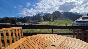 A wooden table and chairs on a balcony with a mountain view. - Cocon Neuf & Vue Panoramique - Portes du Soleil (Vionnaz)