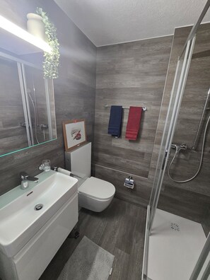 A modern bathroom with a shower, toilet, and sink.