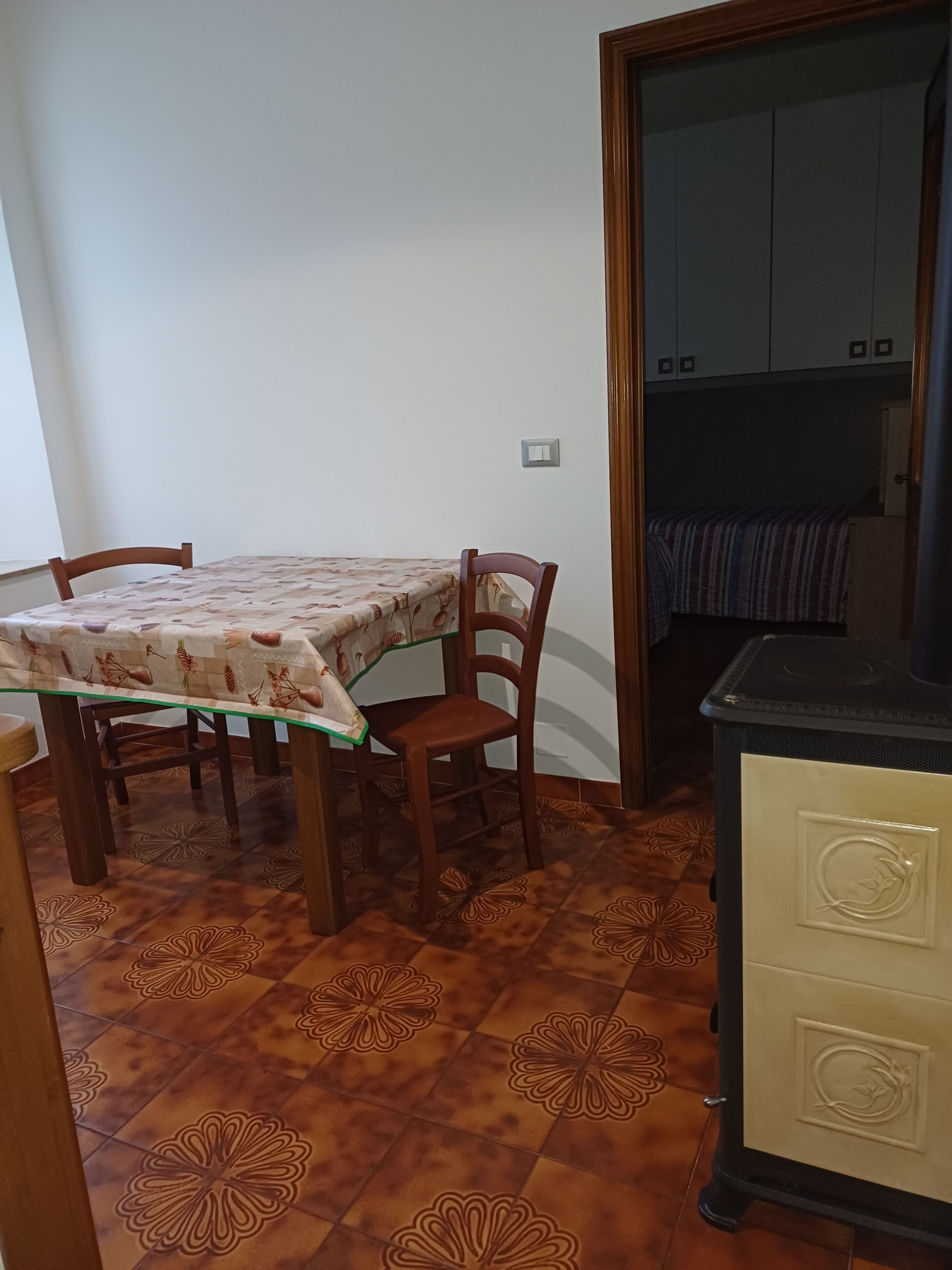 A dining area with a table and chairs, a kitchenette, and patterned floor tiles.