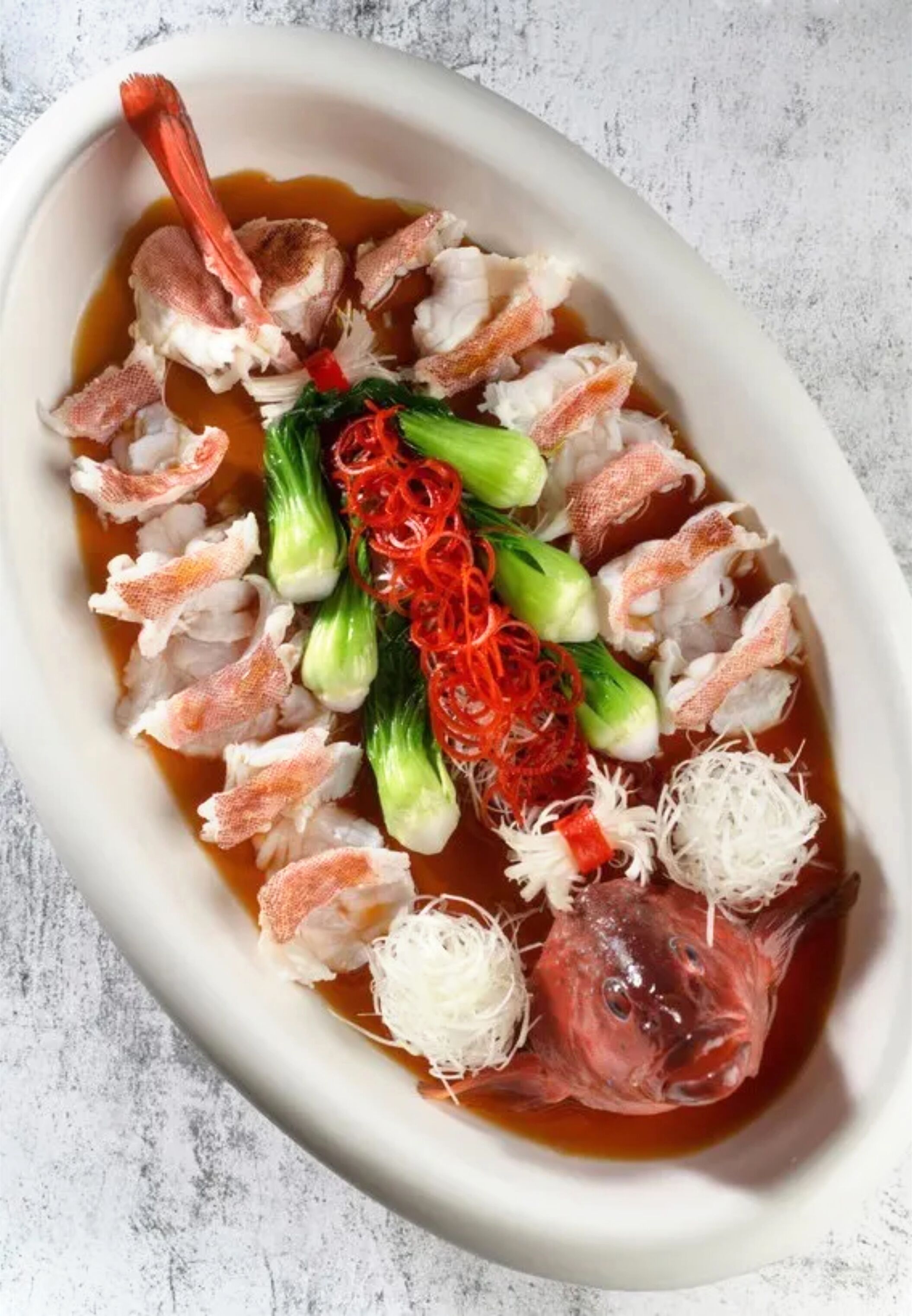 A dish with seafood and vegetables in a white bowl.