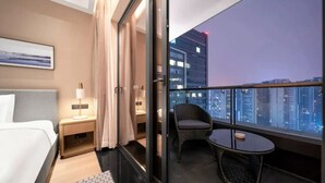 A hotel room with a bed, bedside table, lamp, and a view of the cityscape at dusk. - Hengjing Yushi Hotel (Chengdu)