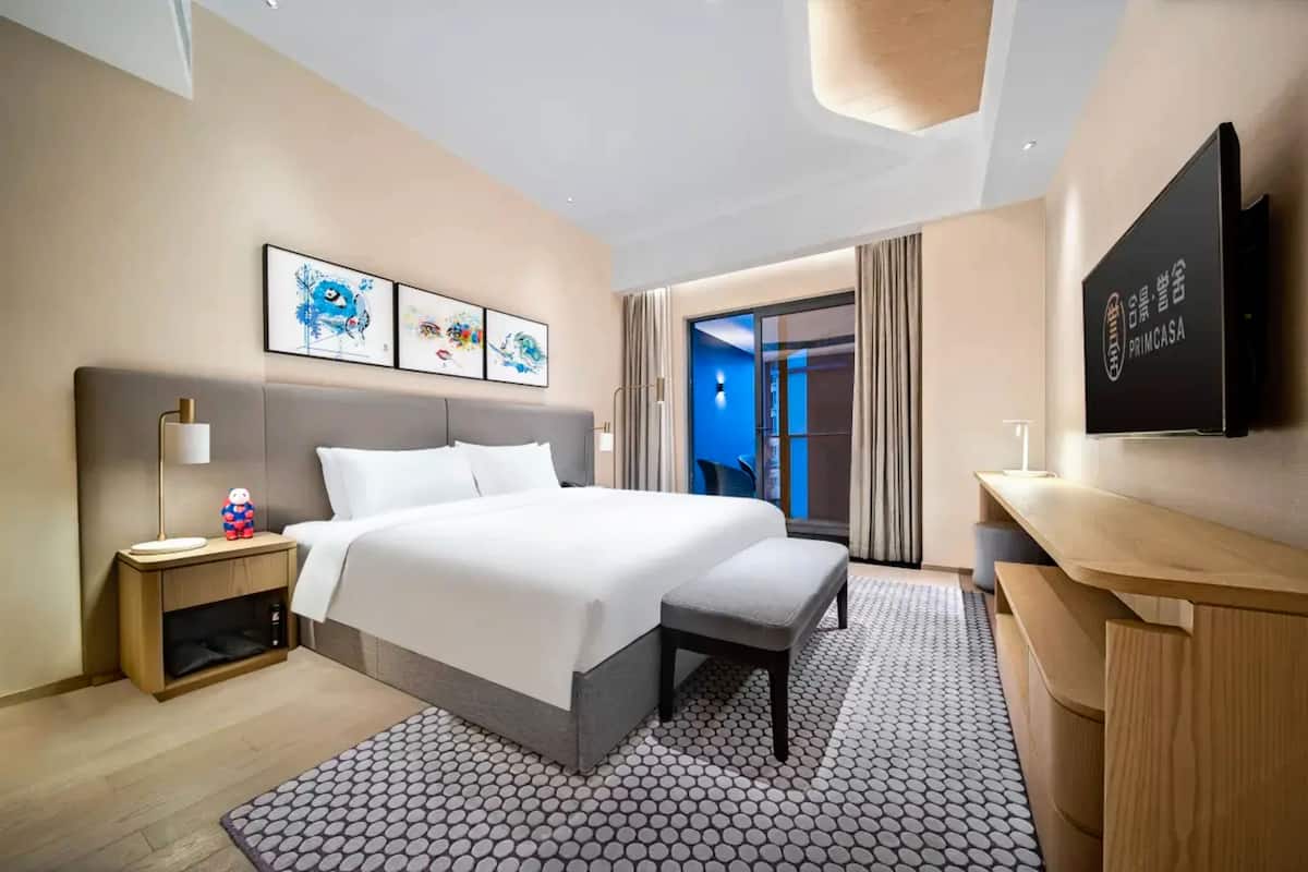 Une chambre d  ’hôtel avec un lit, une table de chevet, une télévision et des œuvres d’art accrochées au mur.