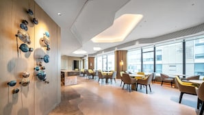 A modern hotel lobby with a wooden wall, a seating area with tables and chairs, and large windows. - Hengjing Yushi Hotel (Chengdu)