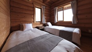 Eine Holzhütte mit zwei Betten und Fenstern mit Vorhängen.