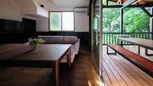 Ein modernes Interieur mit einem Holzesstisch, einer Couch und einem Balkon mit Sitzbank.