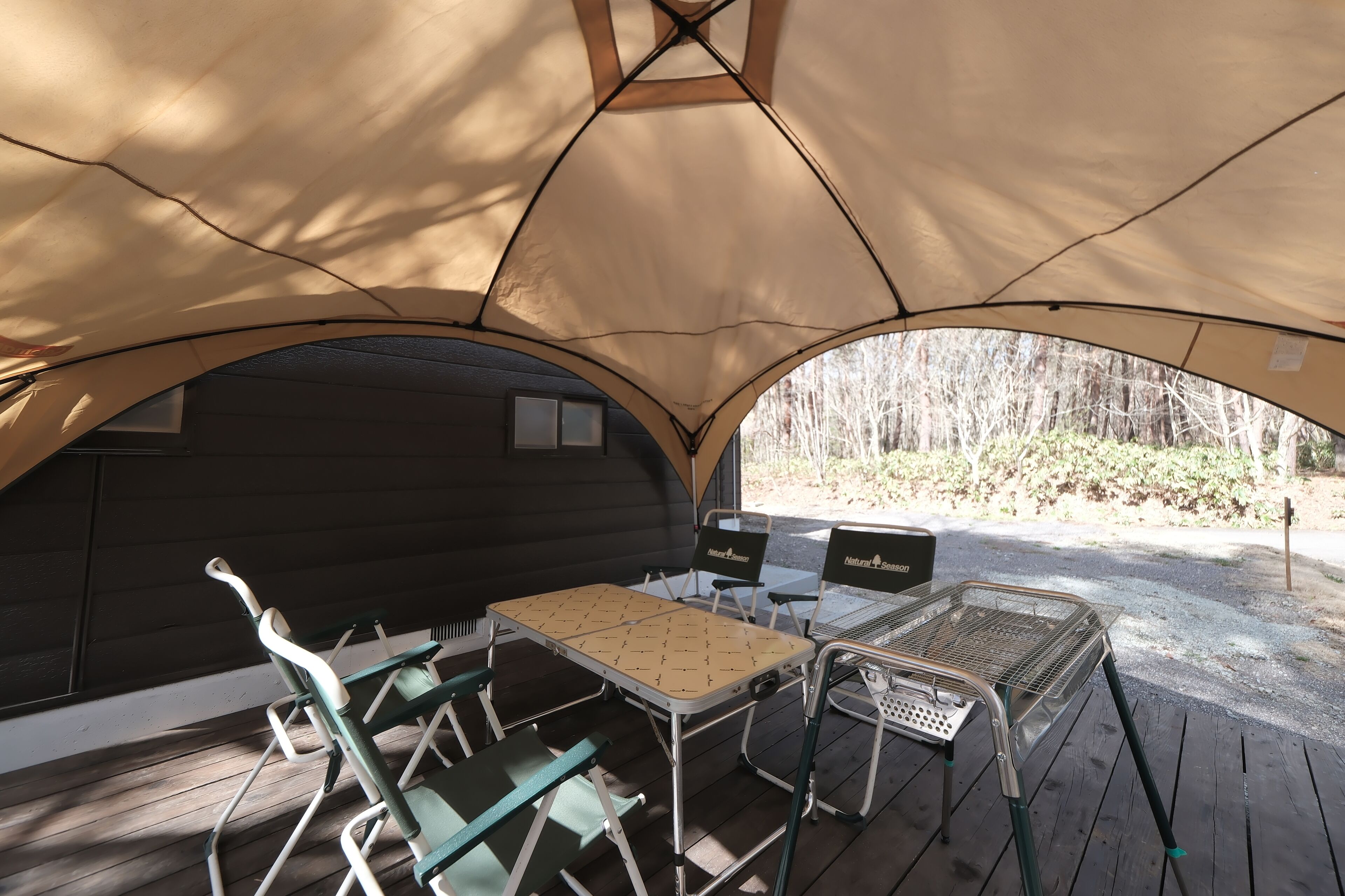 A tented area with a table, chairs, and a grill.