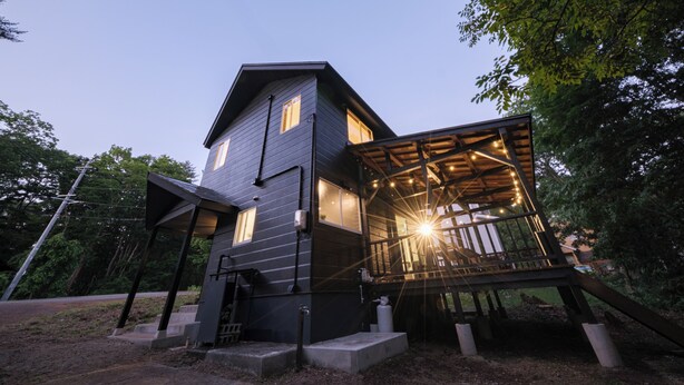 Ein modernes Haus mit einer überdachten Veranda und einer Treppe, die zum Eingang führt.