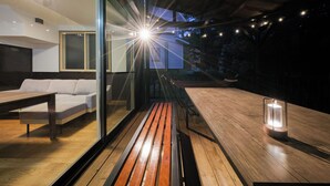 Ein modernes Interieur mit Holzboden, einer Couch, einem Tisch und einer Glastrennwand.