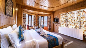 A wooden cabin room with a bed, a table, and a TV. - Bombay Palace (Pahalgam)